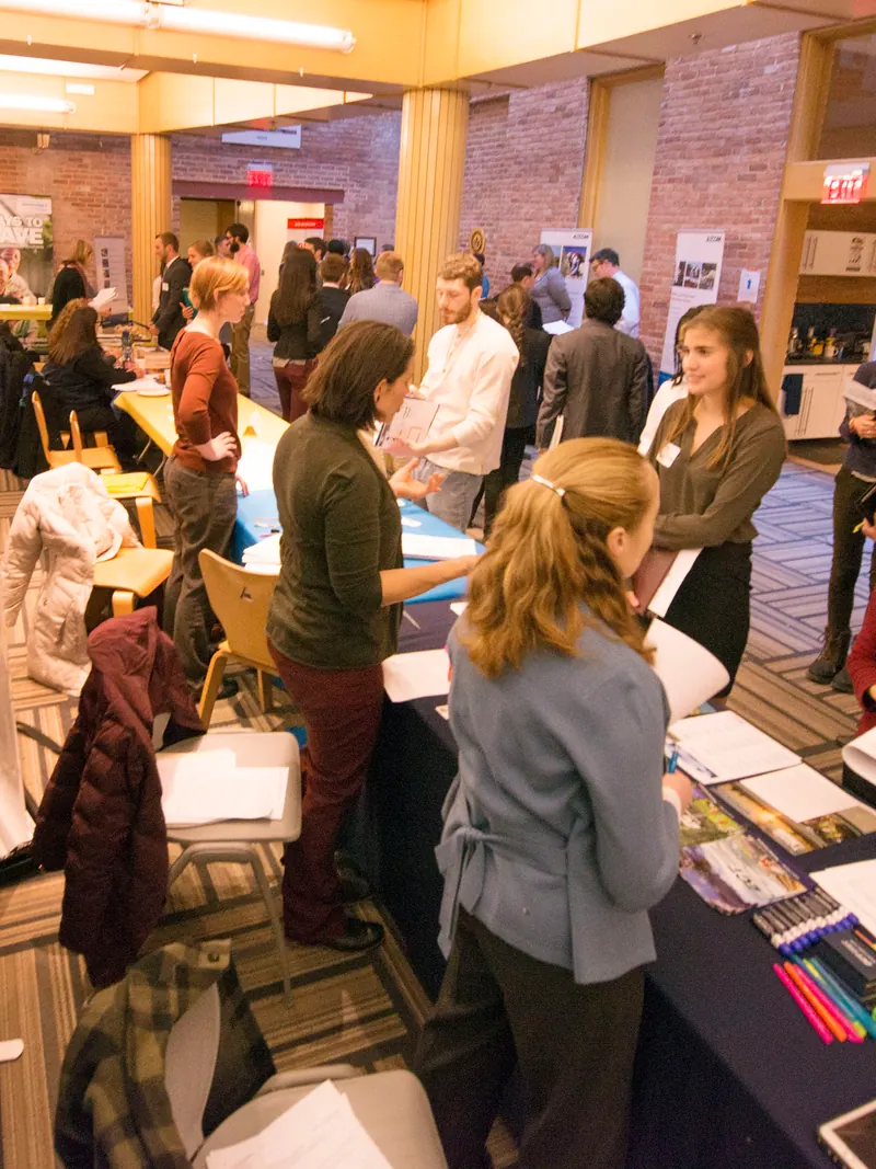 A wide view of a campus fair floor with tables and people moving between them